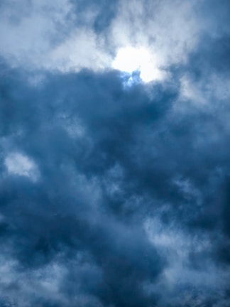 Dark clouds gather in the sky, with a small opening allowing some light to break through, creating a moody and dramatic atmosphere.