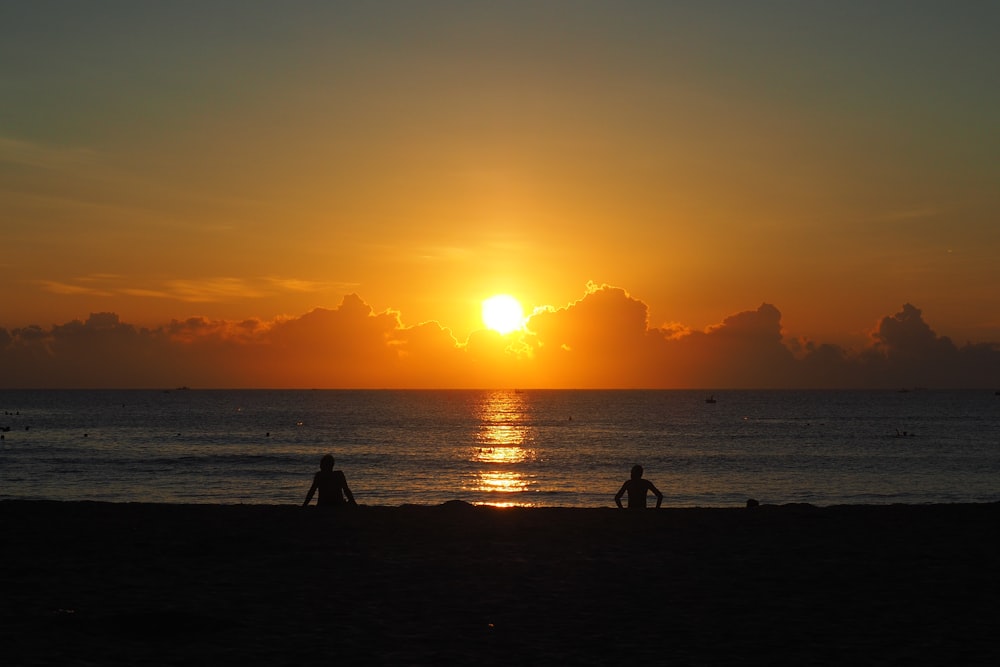 a couple of people standing on top of a beach near the ocean