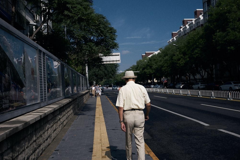 a man walking down a street with a hat on