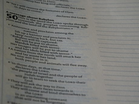 A close-up view of a page from a religious text, likely the Bible, focusing on Jeremiah 50, which is a message about Babylon. The text describes proclamations to be announced among nations, mentioning the capture and shame of Babylon, Bel, and Marduk. The right side of the image shows a partially empty page with dotted lines.