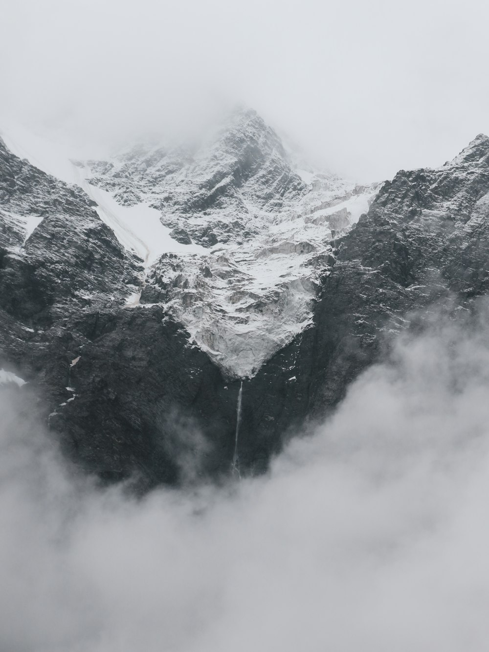 Una montagna coperta di neve circondata da nuvole