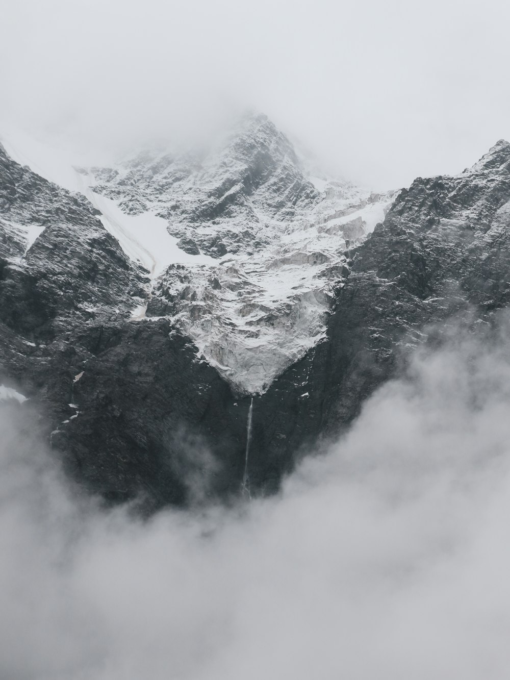 a mountain covered in snow surrounded by clouds