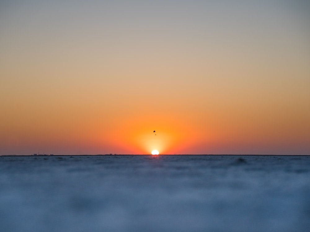the sun is setting over the horizon of the ocean