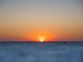 the sun is setting over the horizon of the ocean