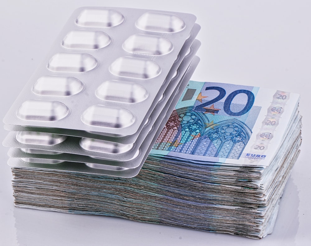 a stack of 20 euro bills next to a pack of 20 pills