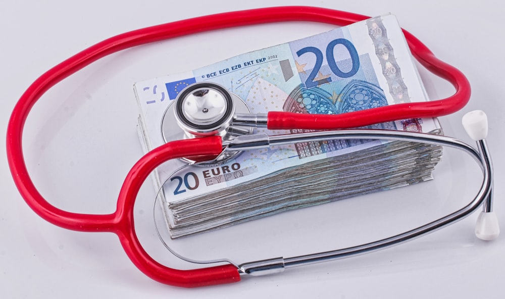a red stethoscope sitting on top of a pile of money