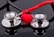 Two stethoscopes with shiny metallic diaphragms are arranged on a reflective black surface, with a small red heart placed in the center between them.
