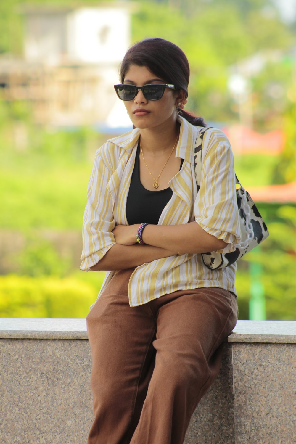 a woman sitting on a wall with her arms crossed