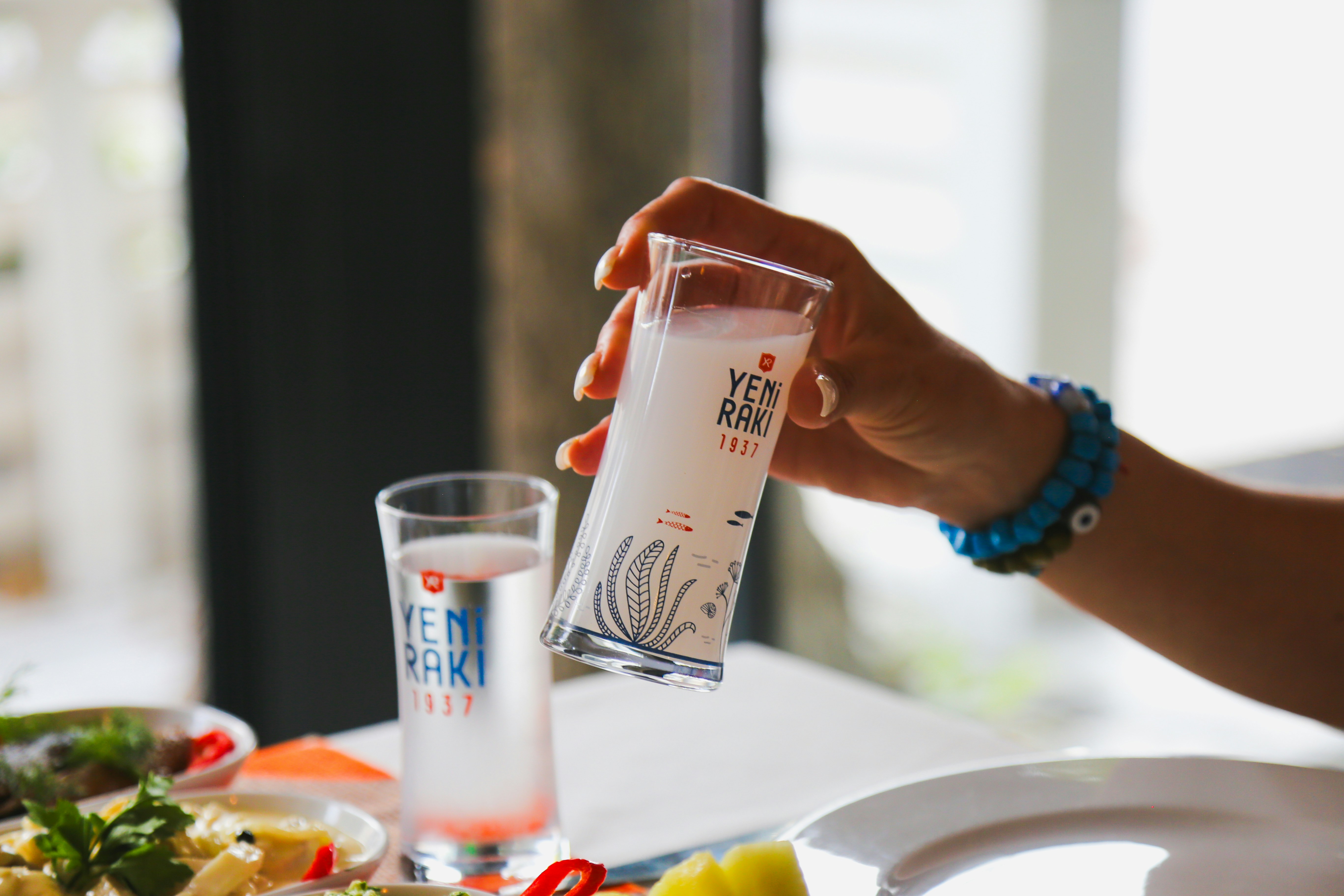 a person holding a bottle of ketchup over a plate of food