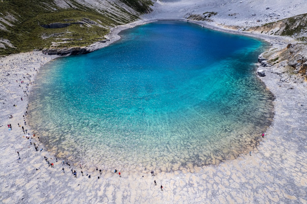 a group of people standing around a blue lake