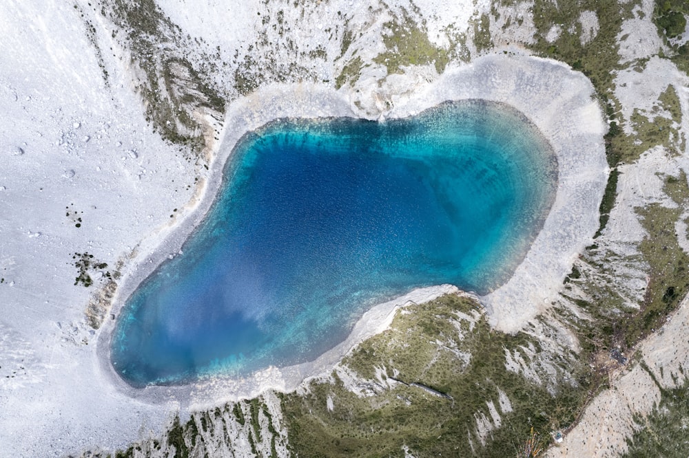 an aerial view of a blue lake surrounded by snow