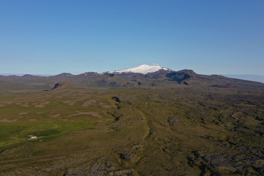 an aerial view of a mountain range with a snow - capped mountain in the distance