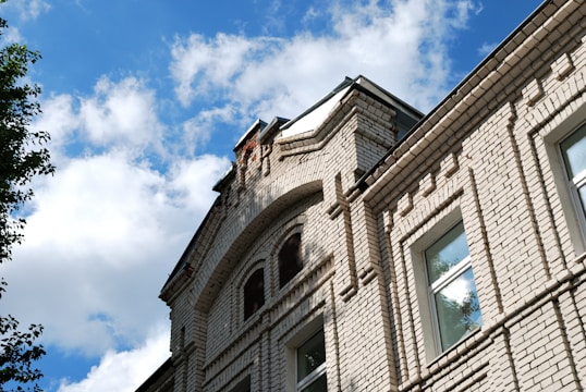 Close-up of skilled workers laying bricks on a residential building under a clear blue sky.