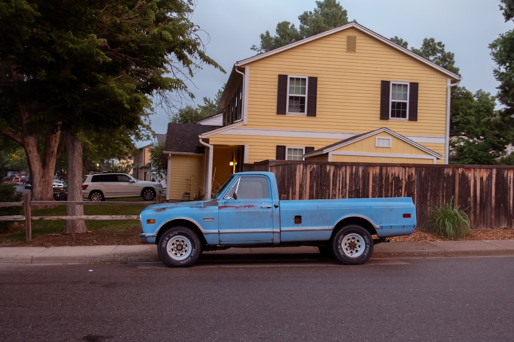 a blue truck parked in front of a yellow house