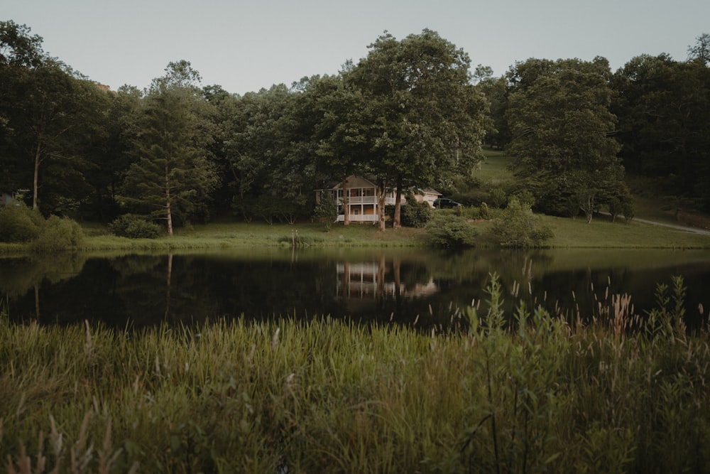 a house sitting on top of a lush green field next to a lake