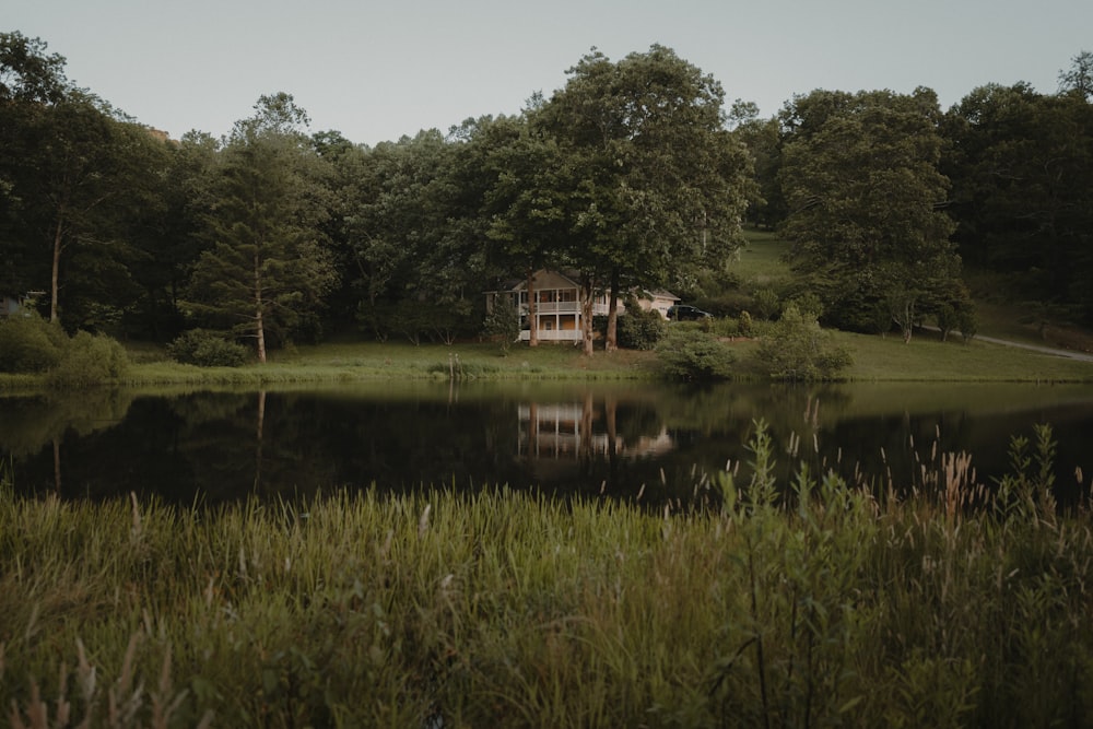 une maison assise au sommet d’un champ verdoyant à côté d’un lac