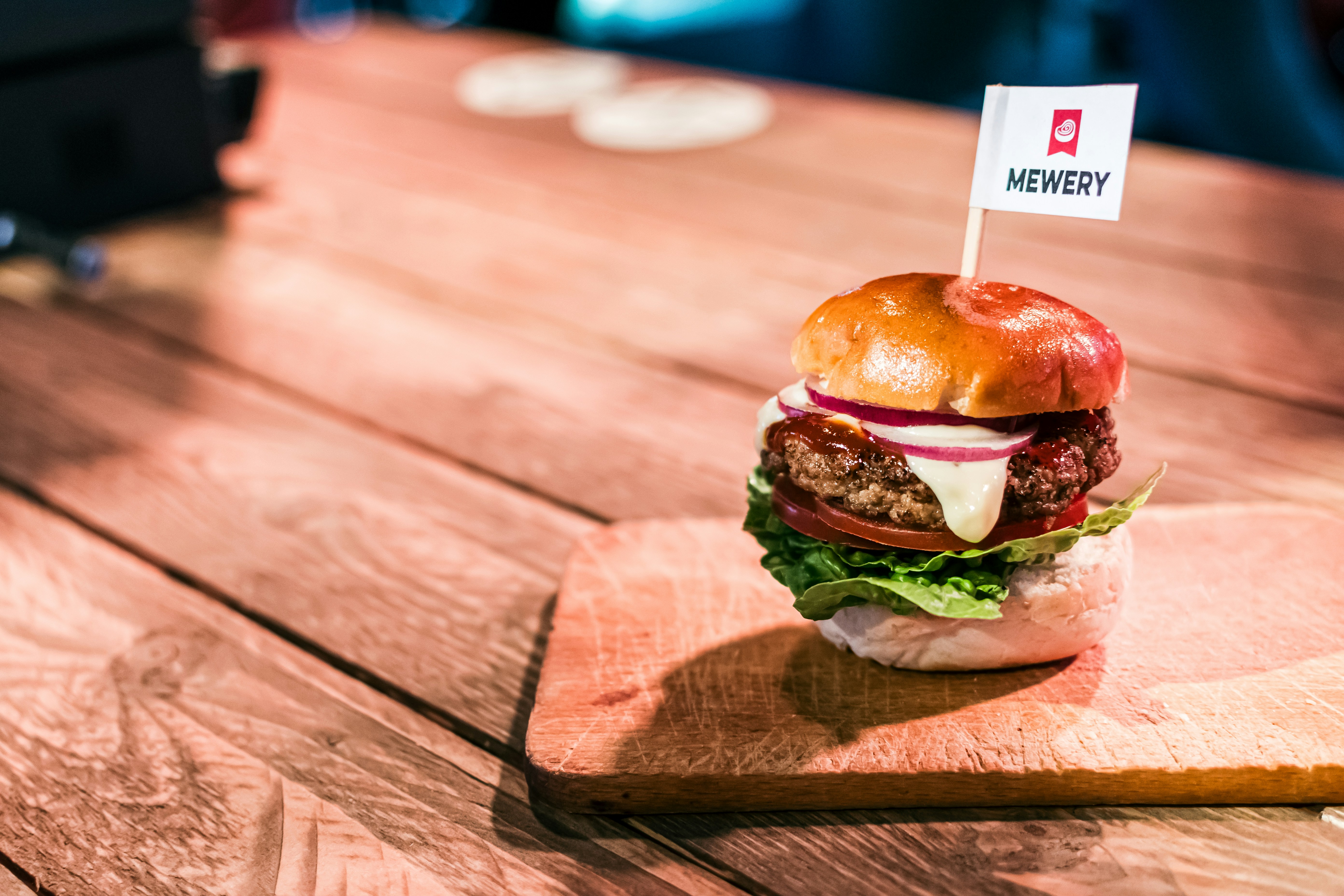 a hamburger sitting on top of a wooden cutting board, Mewery 2023: Cultivated pork burger made from a blend of cultivated pork and microalgae cells