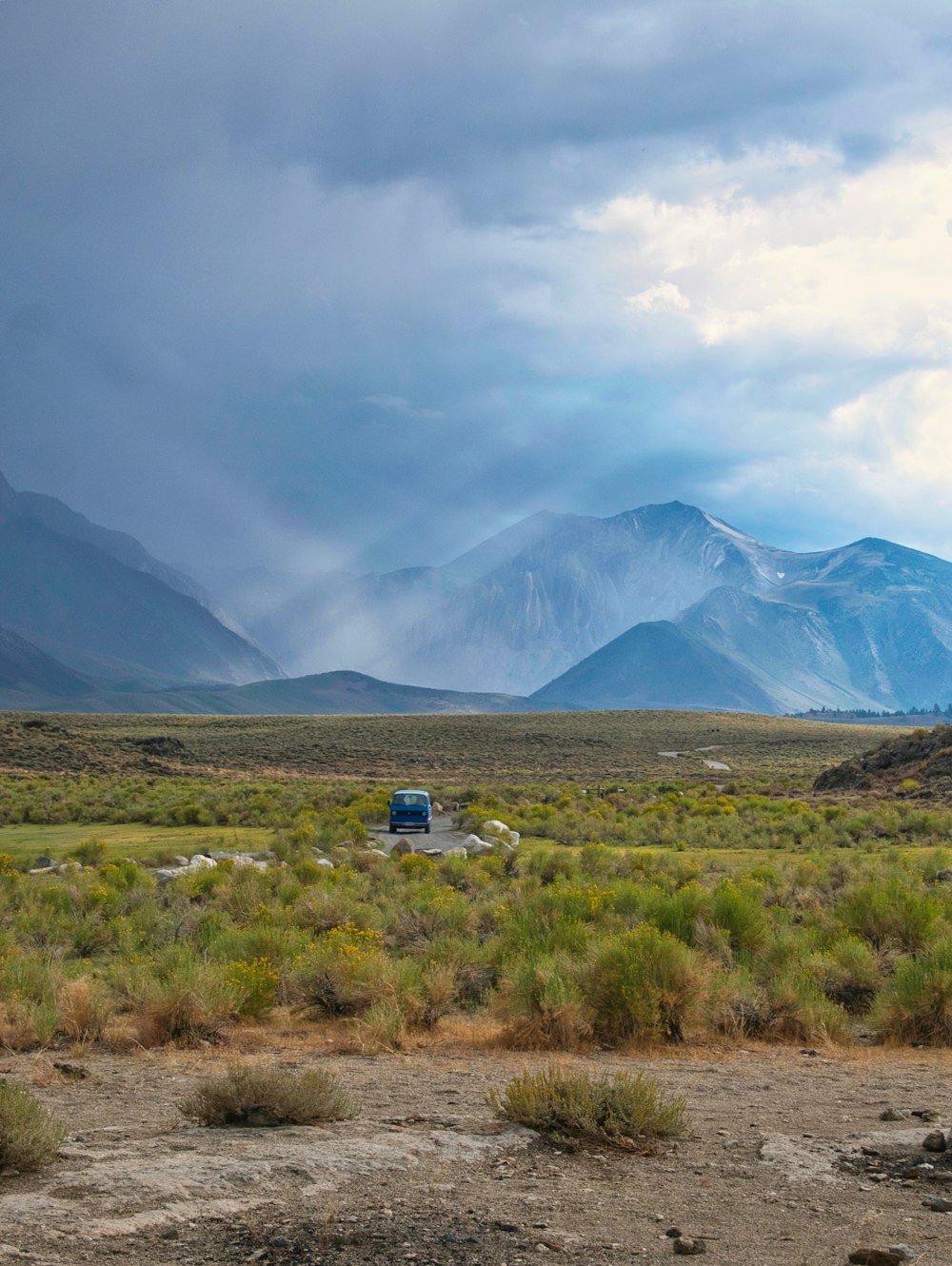 a truck is parked in a field with mountains in the background