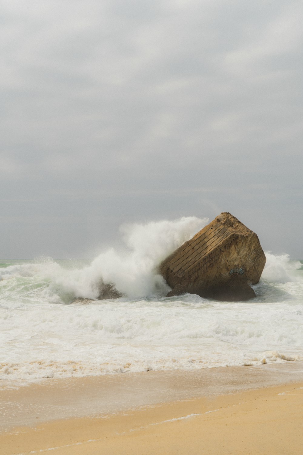 a large rock sitting on top of a sandy beach