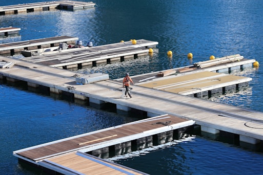 A worker inspecting a large wooden dock on a sunny day.