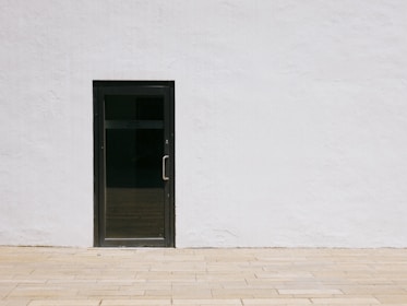 A sleek modern black door standing out against a minimalist white wall.