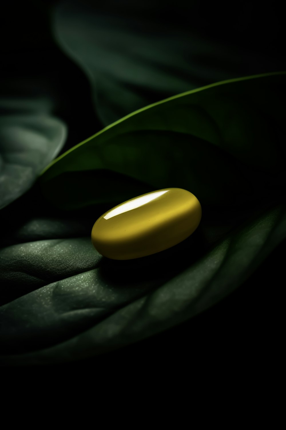a yellow pill sitting on top of a green leaf