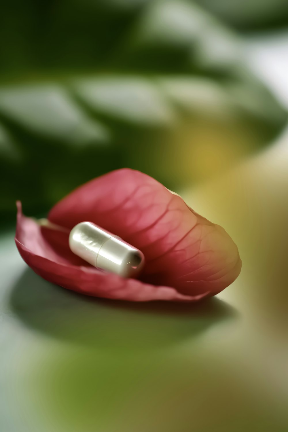 a pill sitting on top of a pink flower