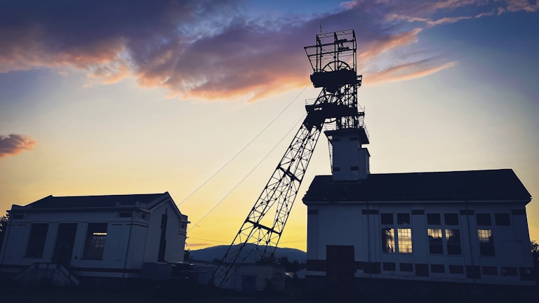 Evening shot of the mine area, with the sun setting behind a line of artisanal miners working diligently.