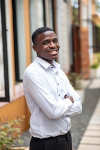 A confident professional standing outdoors, smiling with arms crossed.
