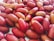 A close-up view of numerous reddish-brown date fruits, showcasing their smooth and elongated texture. Some dates display slight sugar crystallization on their surface, highlighting their natural sweetness.