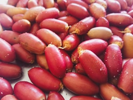 A close-up view of numerous reddish-brown date fruits, showcasing their smooth and elongated texture. Some dates display slight sugar crystallization on their surface, highlighting their natural sweetness.