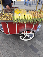 Close-up of a street vendor serving a traditional Mexican elote topped with cheese and chili powder.