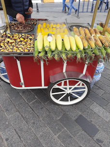 Close-up of a street vendor serving a traditional Mexican elote topped with cheese and chili powder.