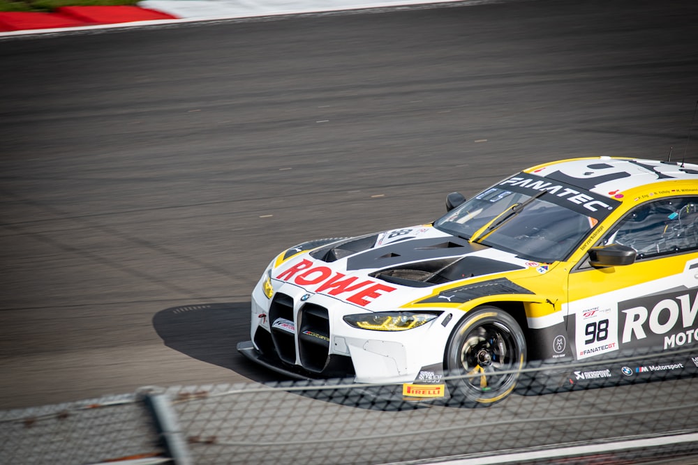 a yellow and white car driving on a race track