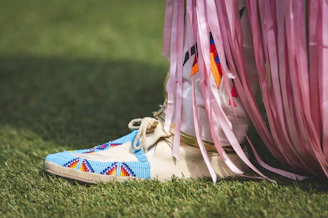 a person's feet with colorful shoes on grass