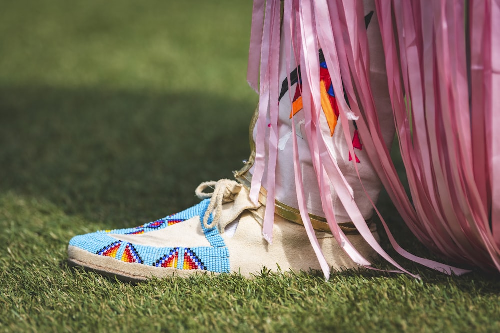 a person's feet with colorful shoes on grass