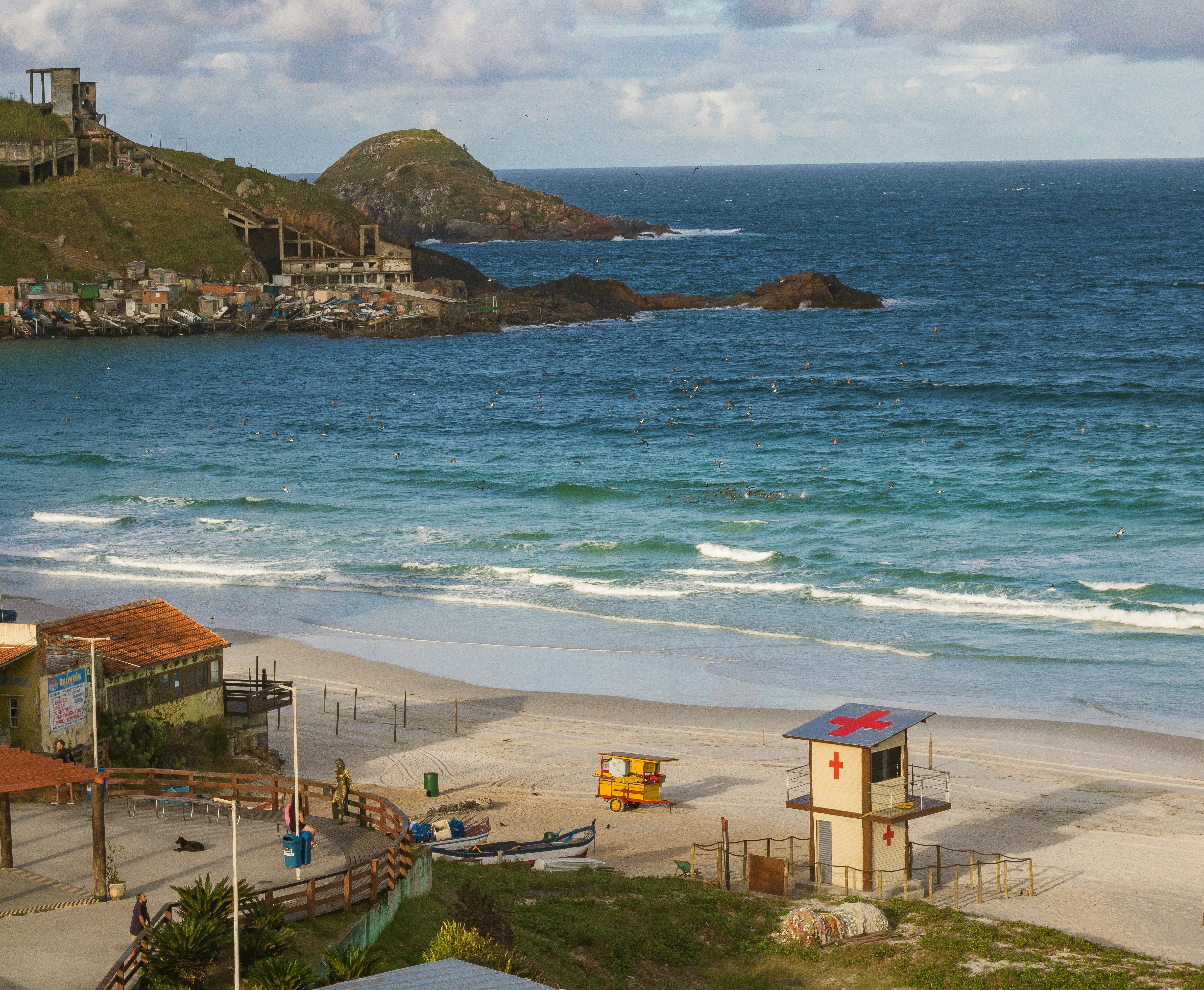 a sandy beach with a lifeguard station and a hill in the background