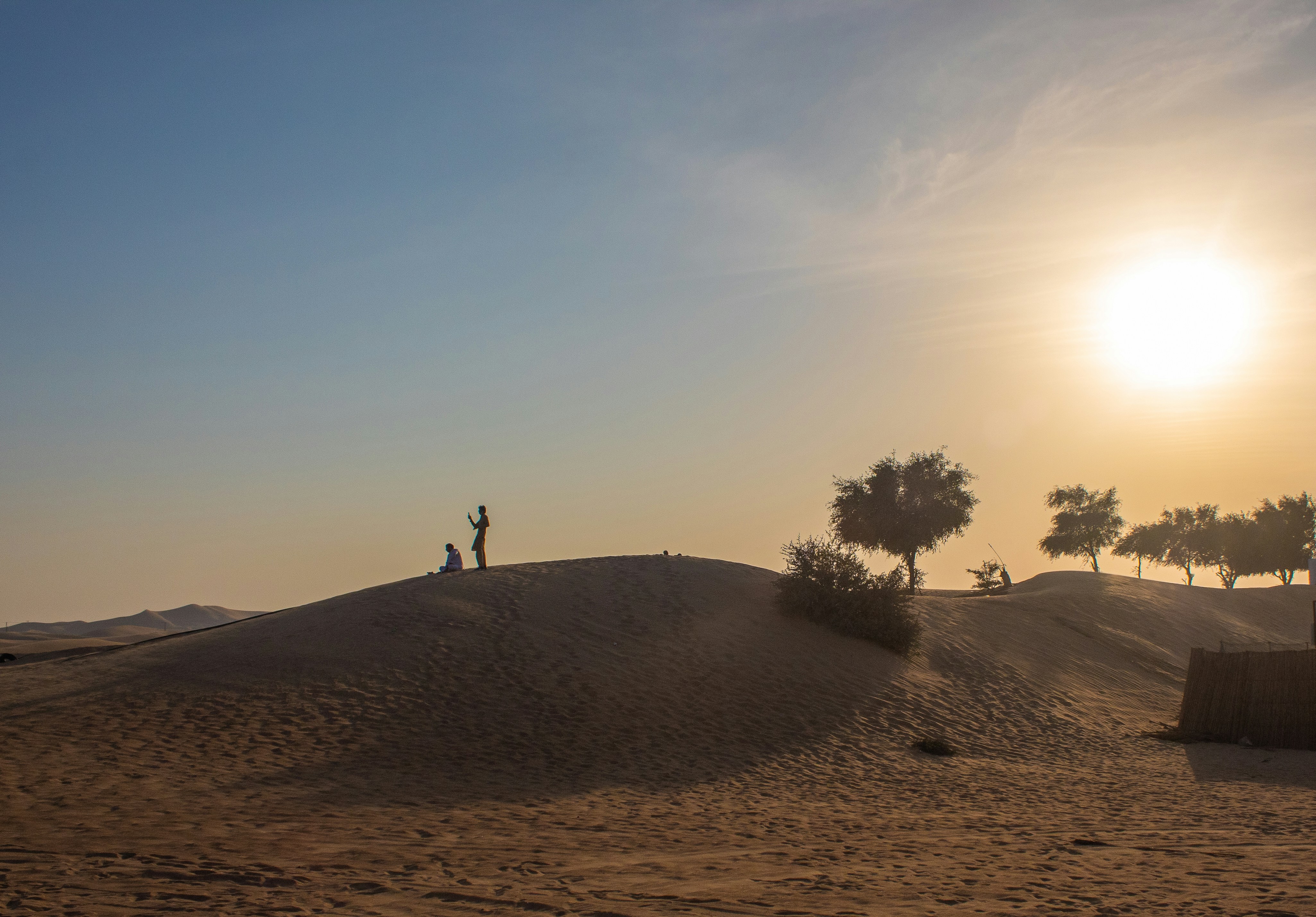 a couple of people standing on top of a sandy hill