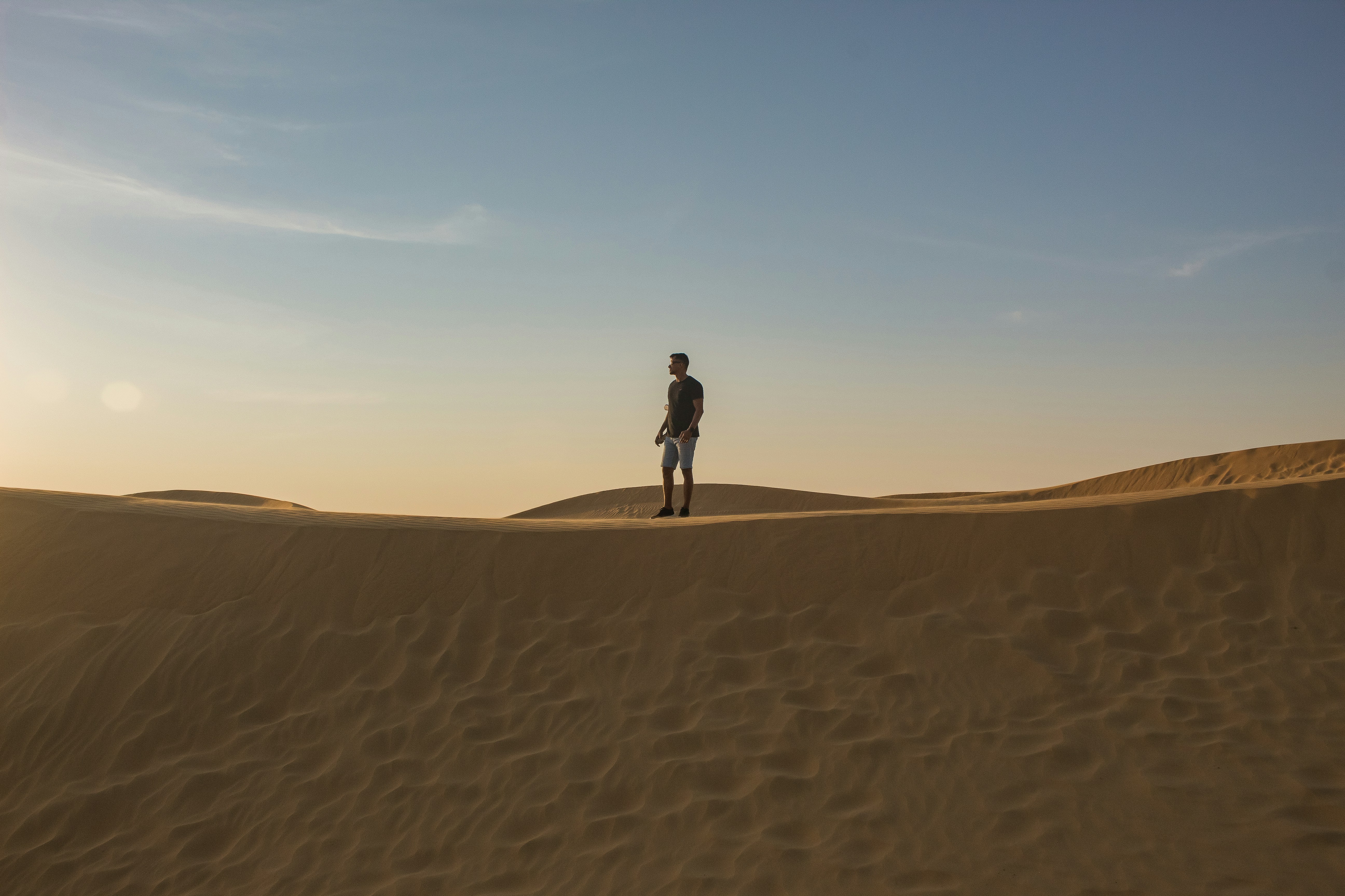 a man standing on top of a sandy dune