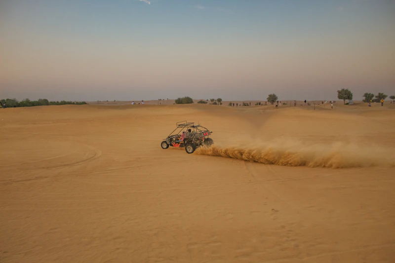 Dune buggy kicking up sand in the Abu Dhabi desert at dusk
