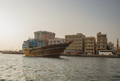 Traditional dhow boats sailing along Dubai Creek under a clear blue sky.