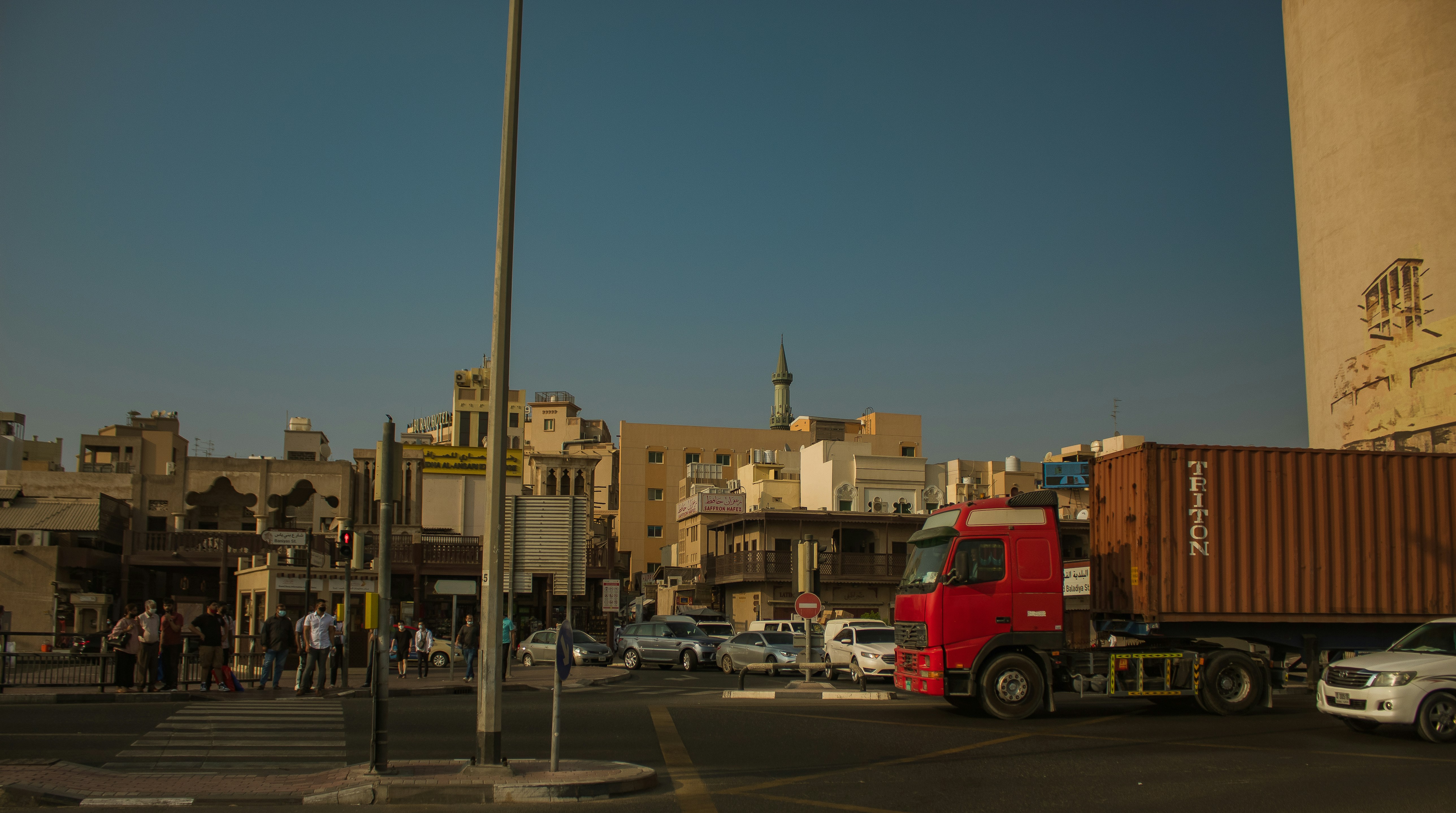 a red truck driving down a street next to tall buildings