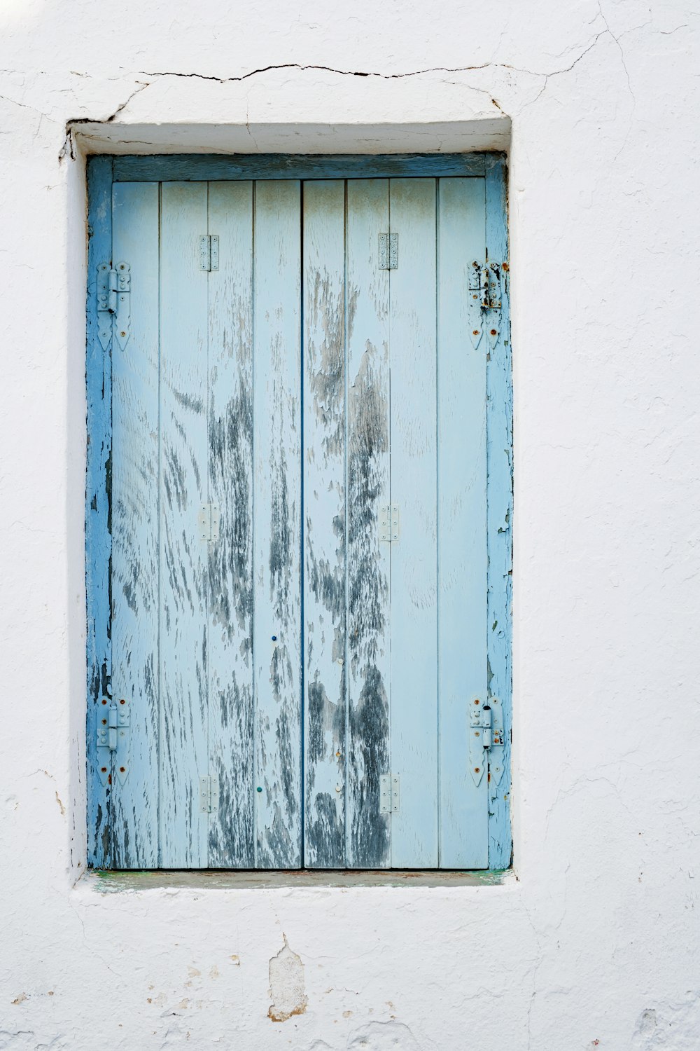 a window with a blue wooden frame on a white wall