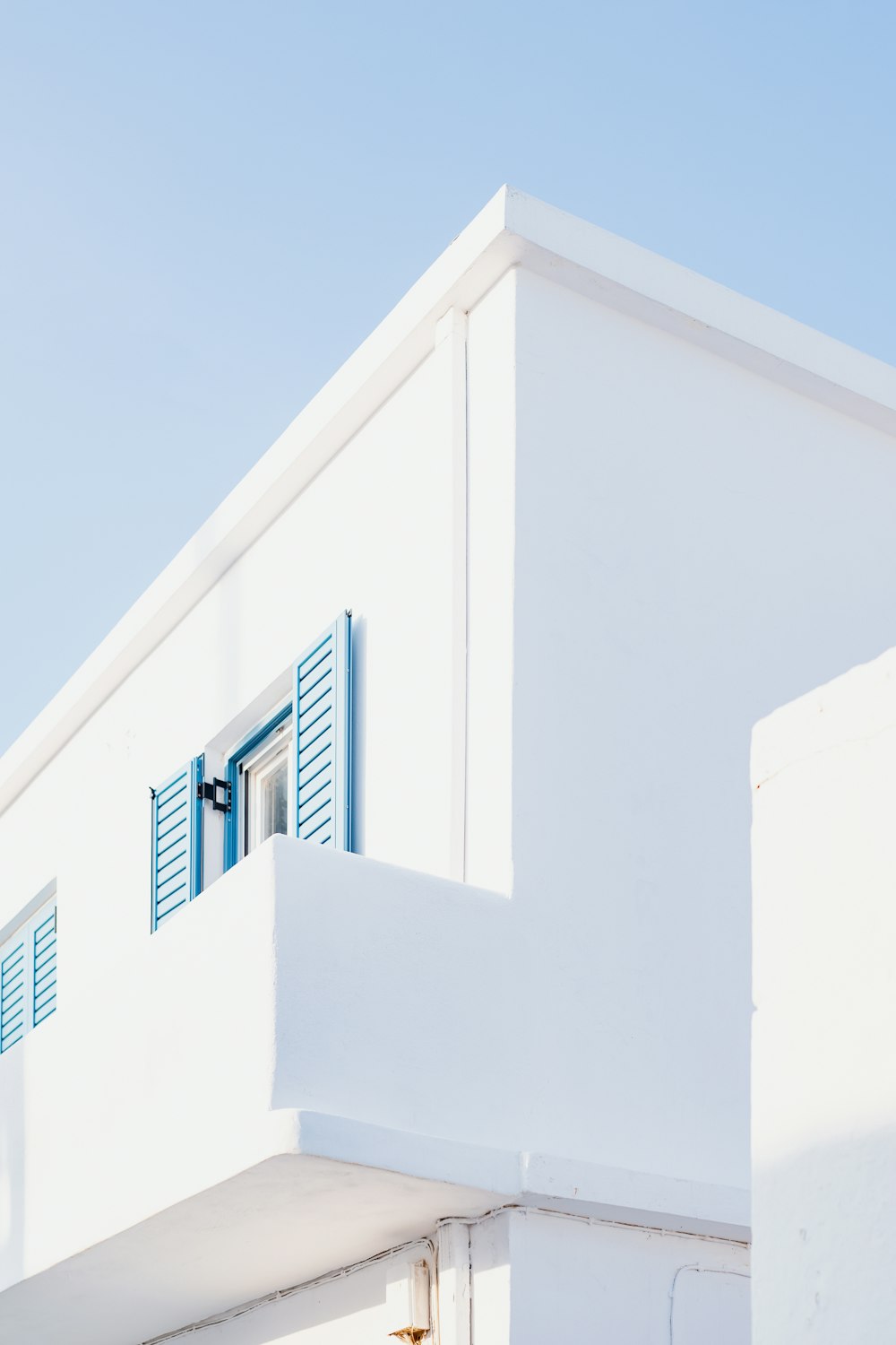 a white building with a blue window and shutters