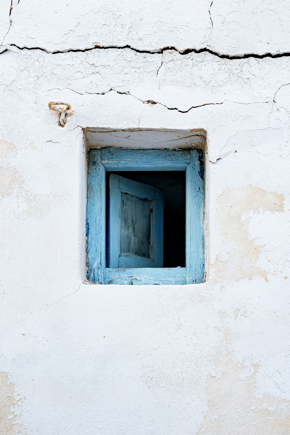 a blue window in a white stucco wall
