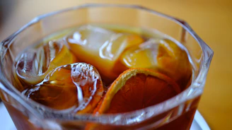 A close-up of a vibrant Thai iced tea in a glass with condensation on the outside.