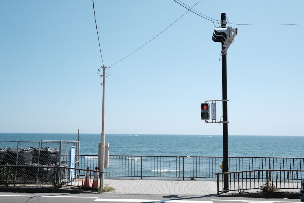 a traffic light sitting on the side of a road next to the ocean