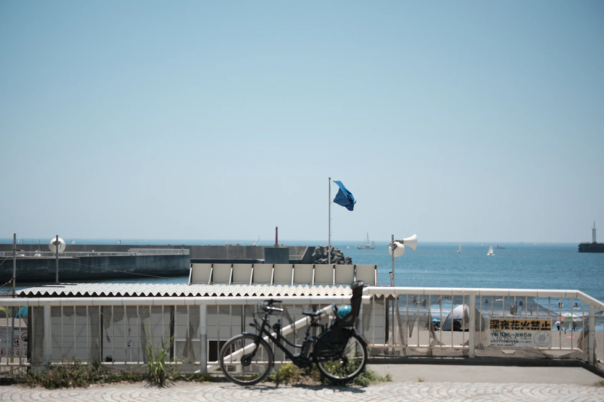 Bicycle parked by a harbour fence with the sea and breakwater beyond