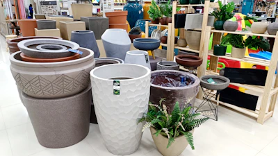 Various metal and polyethylene planters arranged artistically in a sunlit showroom