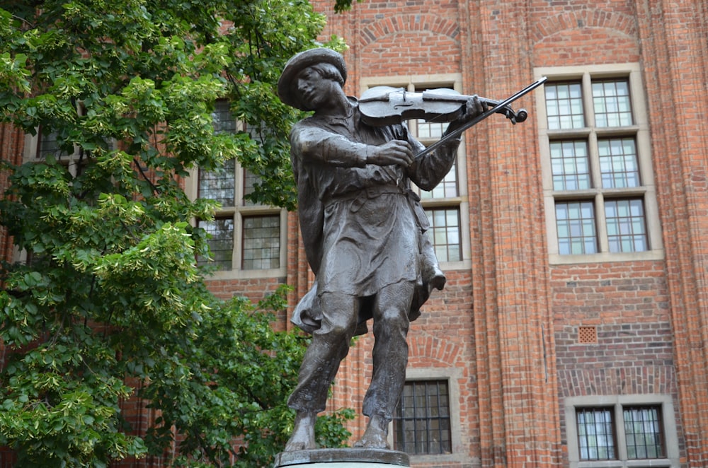 a statue of a man holding a violin in front of a building